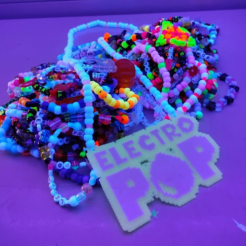 Colorful beaded bracelets on a purple surface with 'Electro Pop' sign.